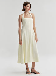 Woman wearing a beige halter neck dress on a plain background