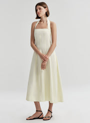 Woman wearing a beige halter neck dress on a plain background