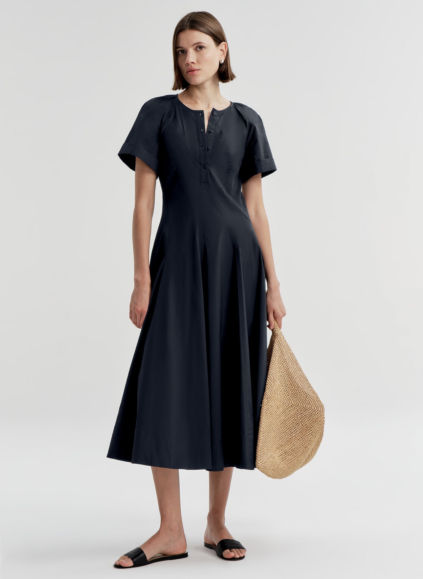 Woman wearing a dark blue short sleeve dress on a white background