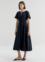 Woman wearing a dark blue short sleeve dress on a white background