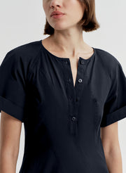 Woman wearing a dark blue short sleeve dress on a white background