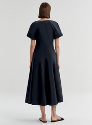 Woman wearing a dark blue short sleeve dress on a white background