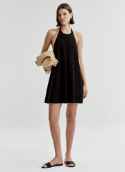 Woman wearing a black halter neck dress on a white background