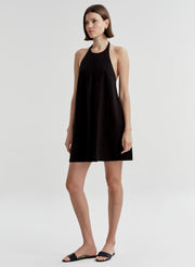 Woman wearing a black halter neck dress on a white background