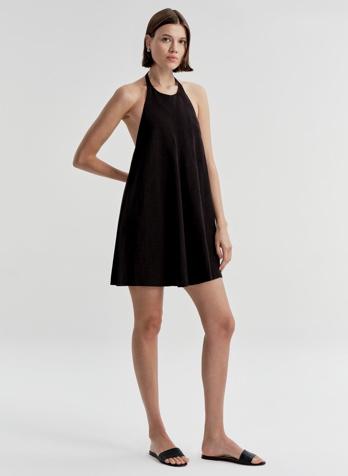 Woman wearing a black halter neck dress on a white background