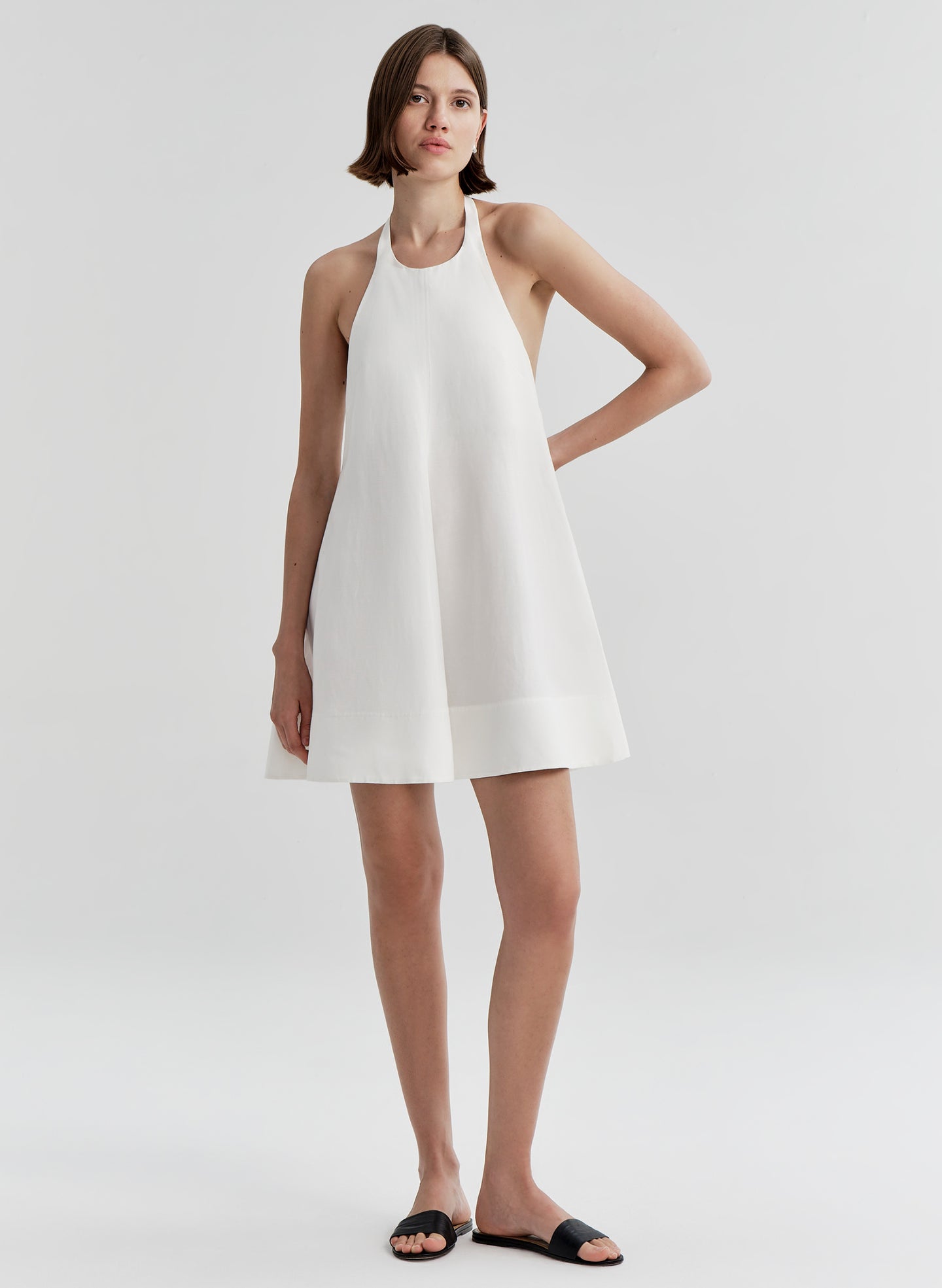 Woman wearing a white halter neck dress on a plain background