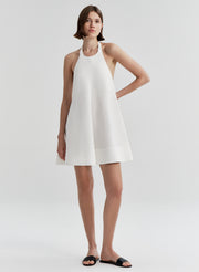 Woman wearing a white halter neck dress on a plain background