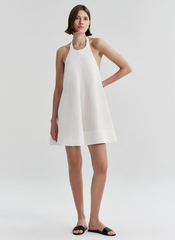Woman wearing a white halter neck dress on a plain background