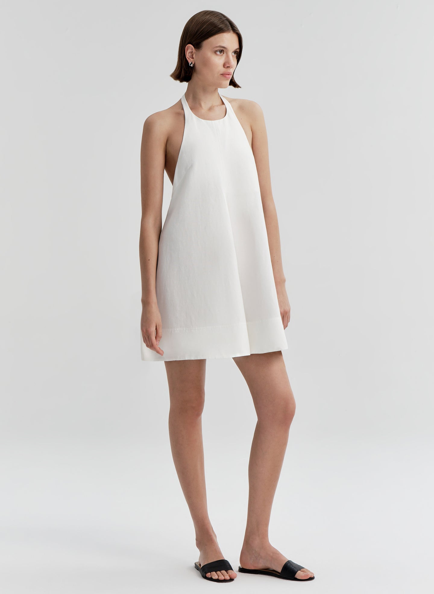 Woman wearing a white halter neck dress on a plain background