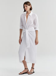 Woman wearing a white shirt dress with a knot detail on a white background