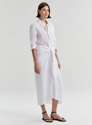 Woman wearing a white shirt dress with a knot detail on a white background