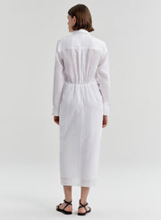 Woman wearing a white shirt dress with a knot detail on a white background