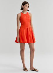 Woman wearing a bright orange sleeveless dress on a white background