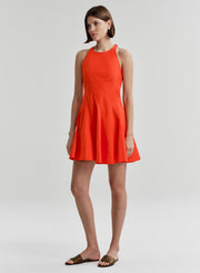 Woman wearing a bright orange sleeveless dress on a white background