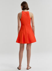 Woman wearing a bright orange sleeveless dress on a white background