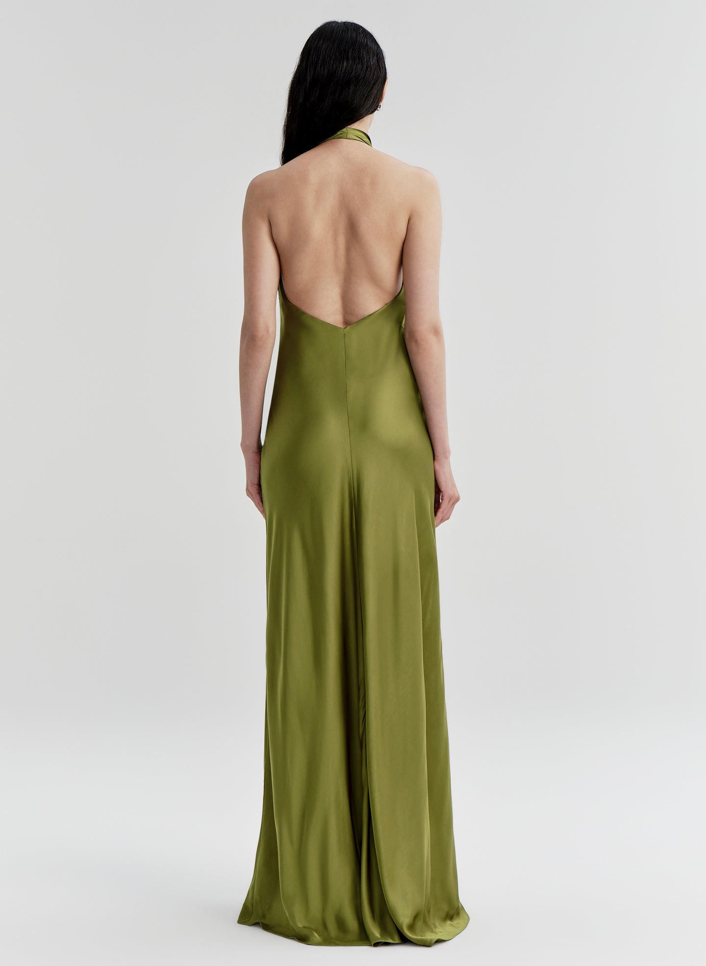 Woman wearing a green gown with a backless design on a white background