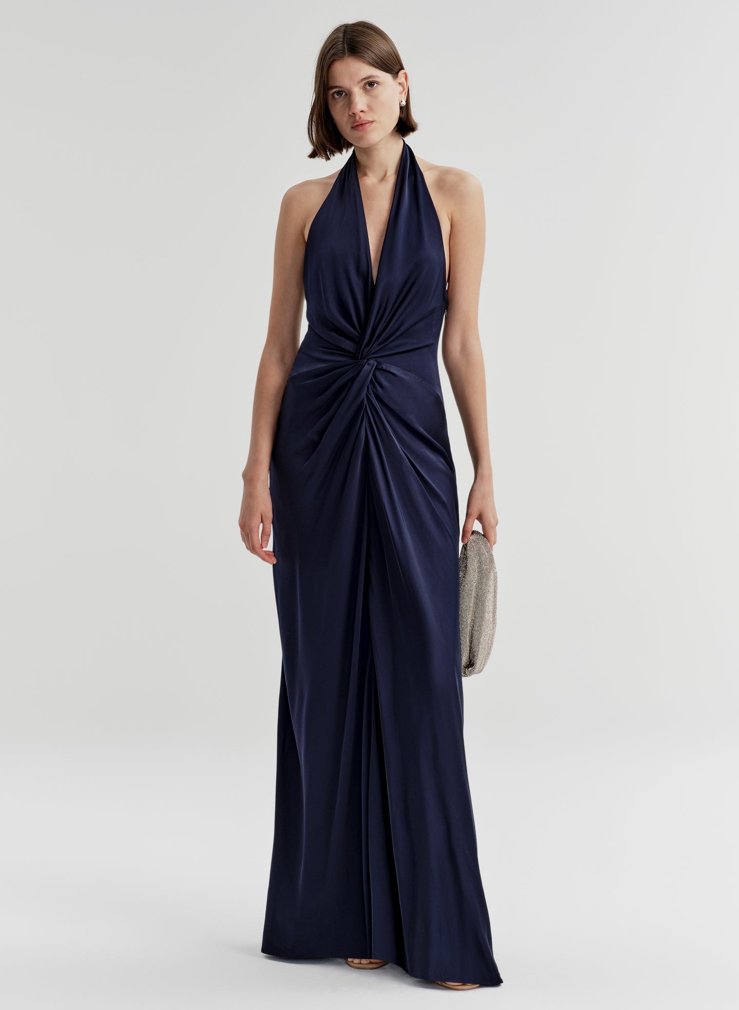 Woman wearing a navy blue halter neck gown on a white background