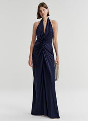 Woman wearing a navy blue halter neck gown on a white background