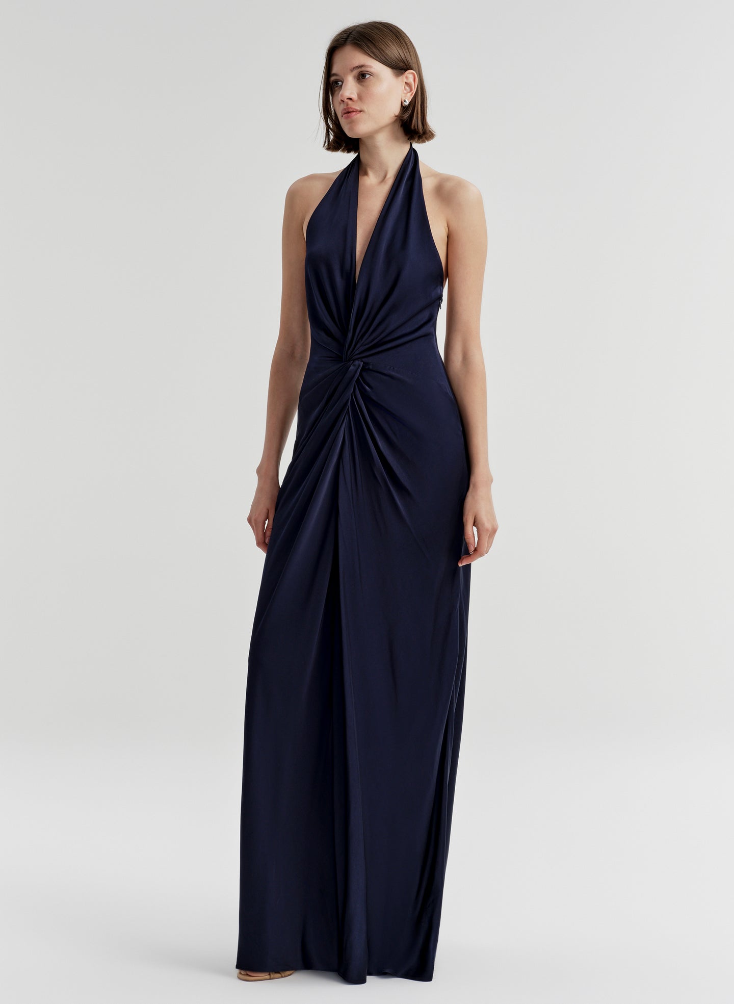 Woman wearing a navy blue halter neck gown on a white background