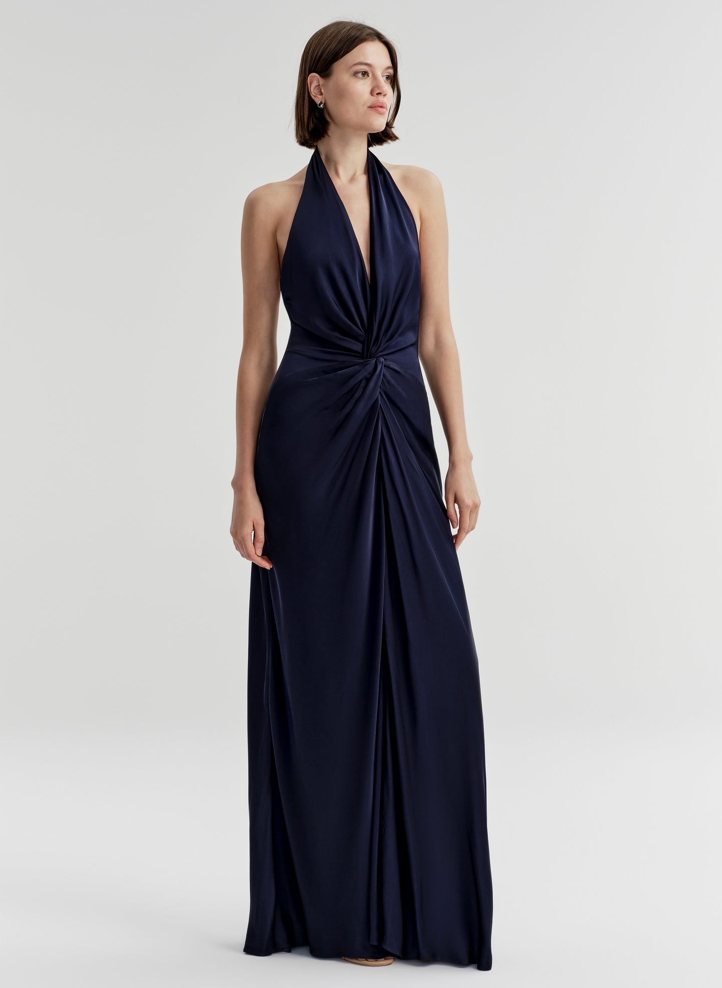 Woman wearing a navy blue halter neck gown on a white background