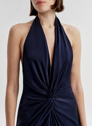 Woman wearing a navy blue halter neck gown on a white background
