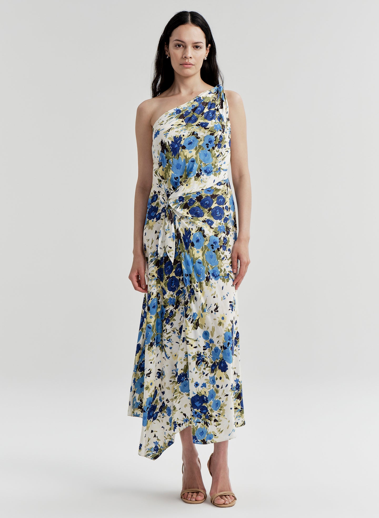 Woman wearing a floral one-shoulder dress on a plain background