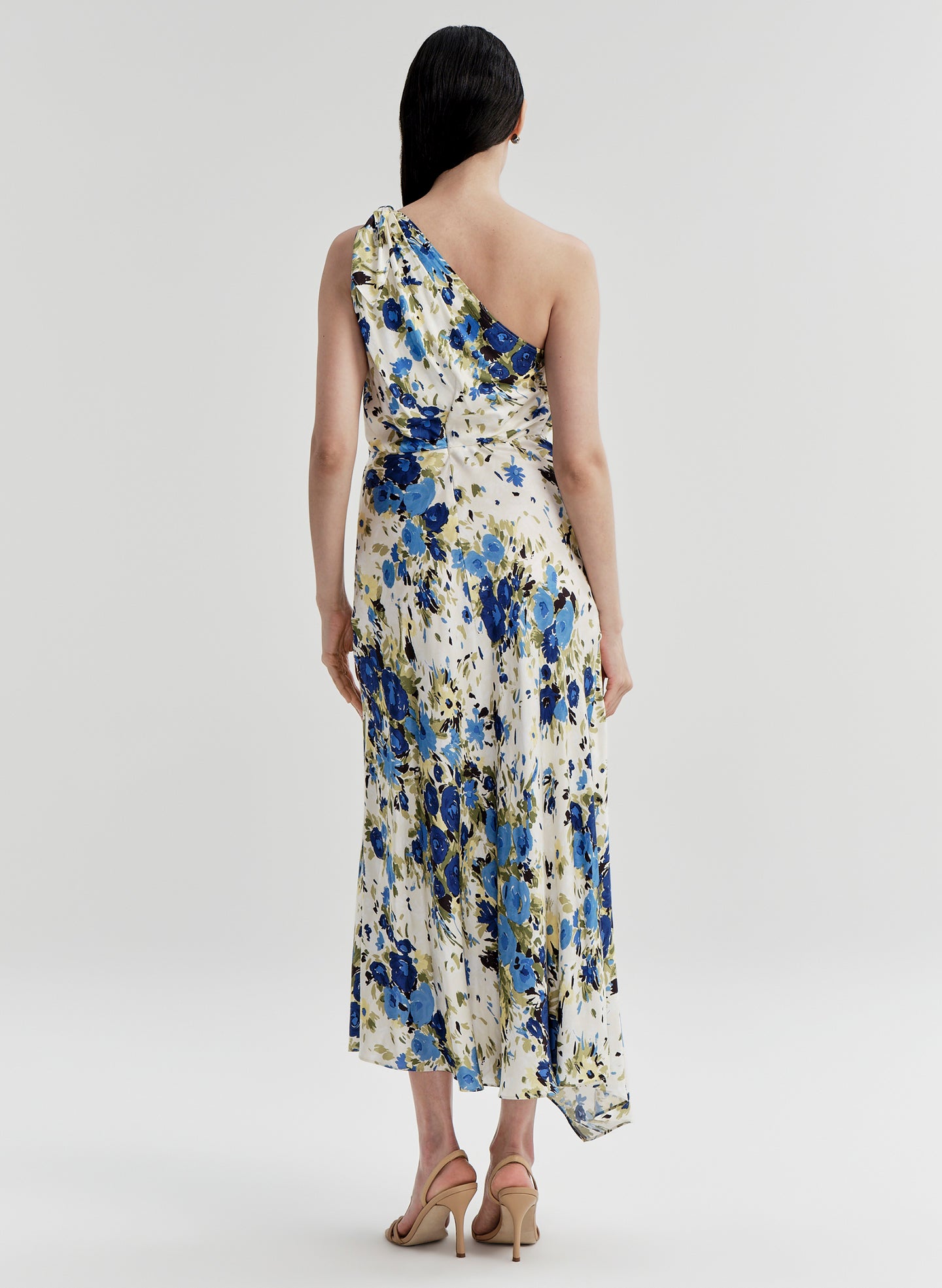 Woman wearing a floral one-shoulder dress on a plain background