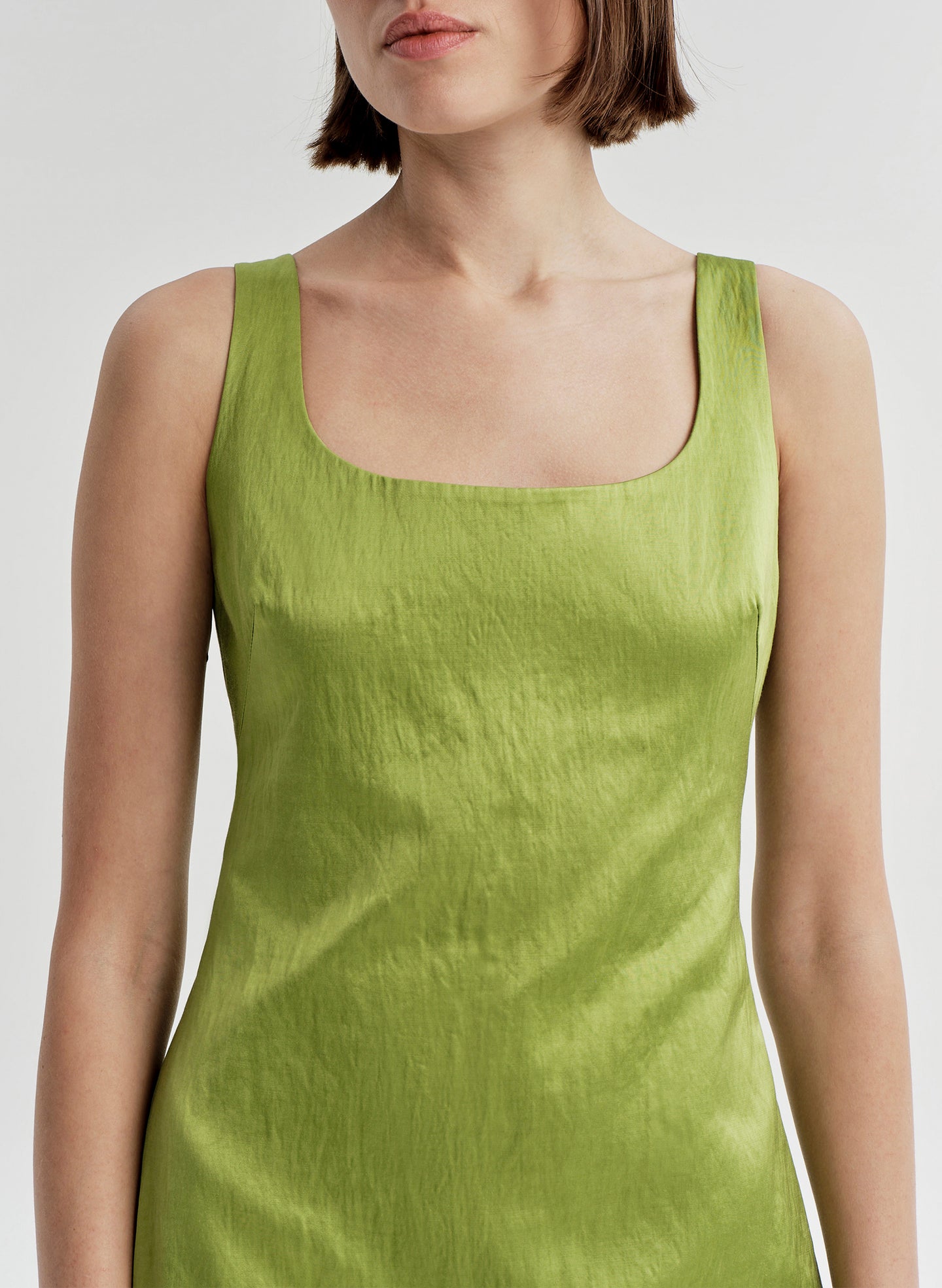Woman wearing a green sleeveless dress on a white background