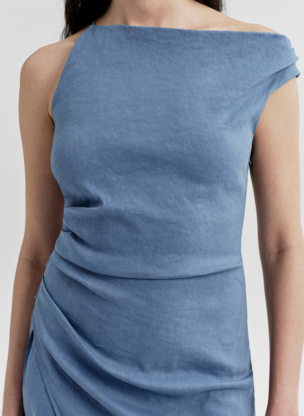 Woman wearing a blue one-shoulder dress on a light gray background