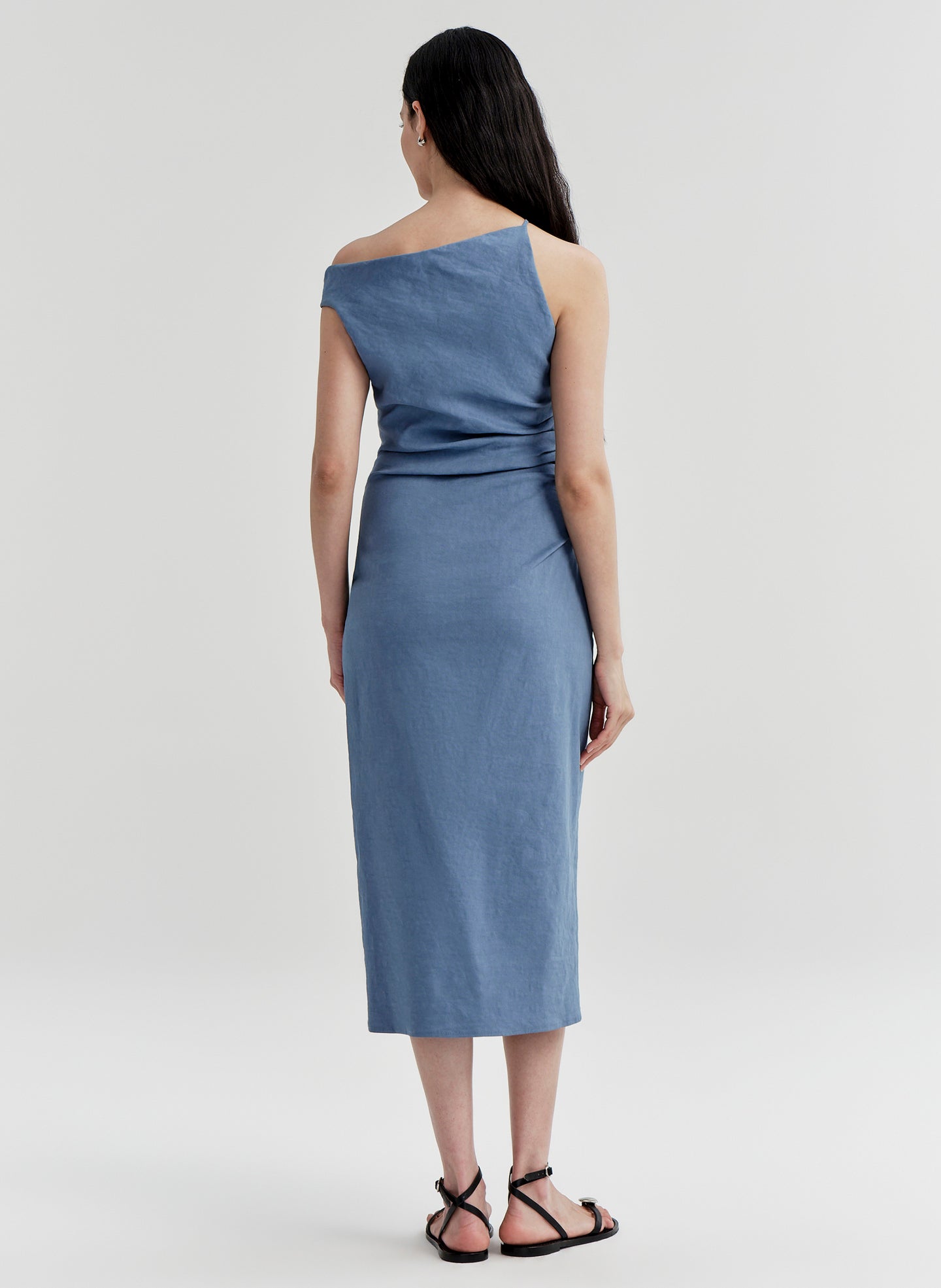 Woman wearing a blue one-shoulder dress on a light gray background