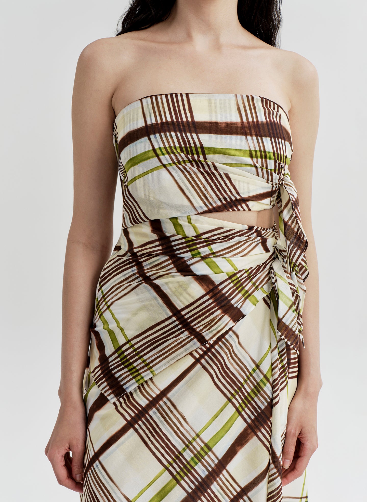 Woman wearing a cotton plaid strapless dress on a white background