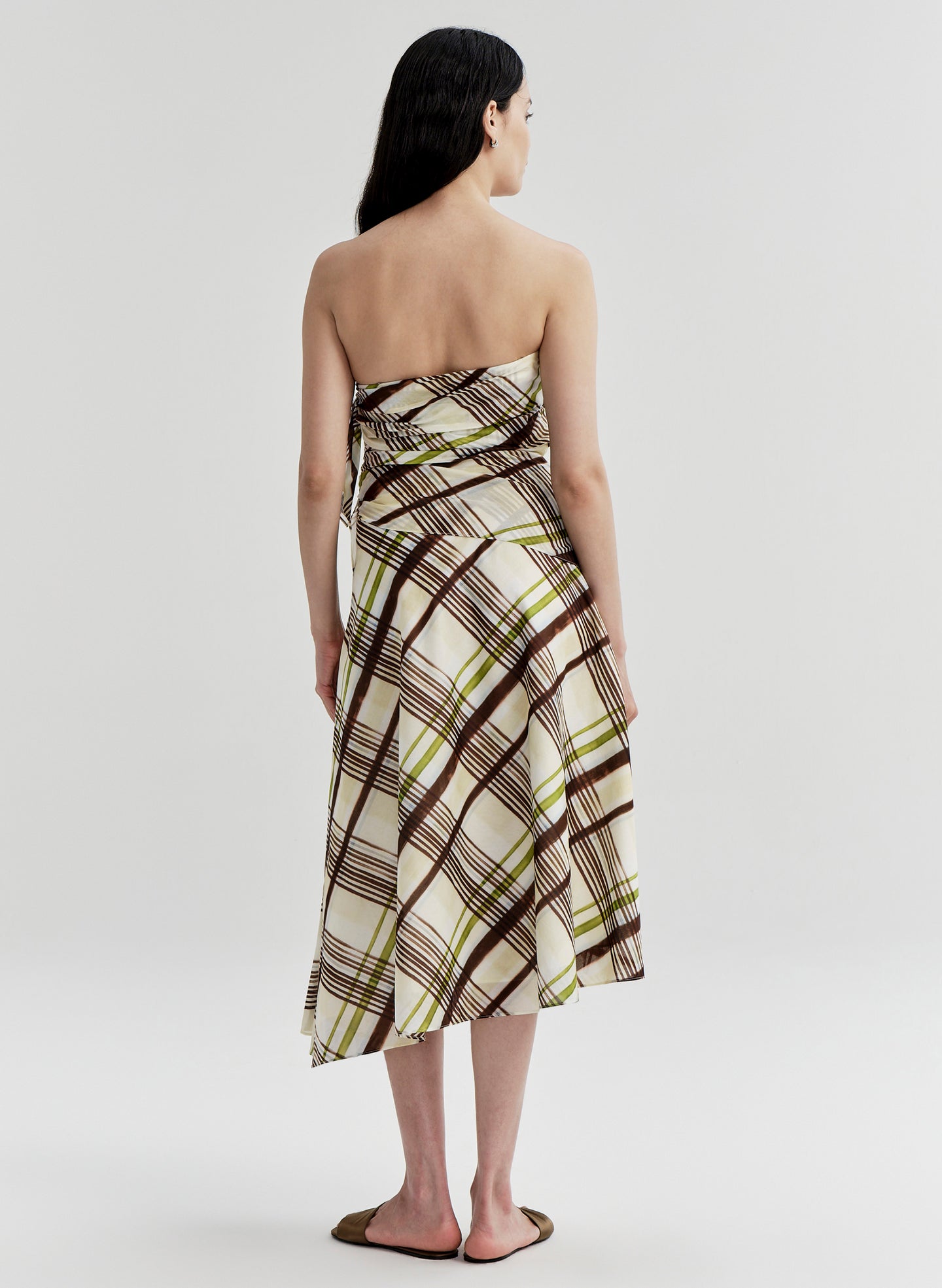 Woman wearing a cotton plaid strapless dress on a white background