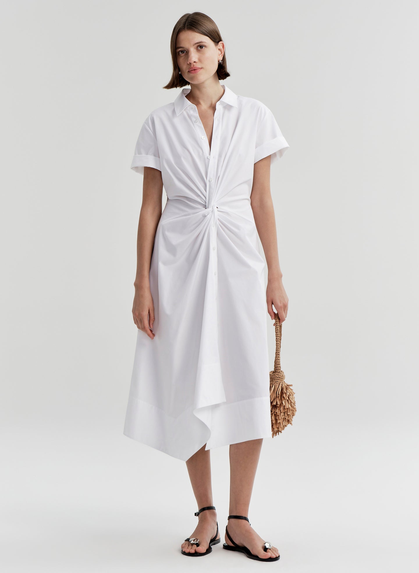Woman wearing a white dress with a knot detail on a white background