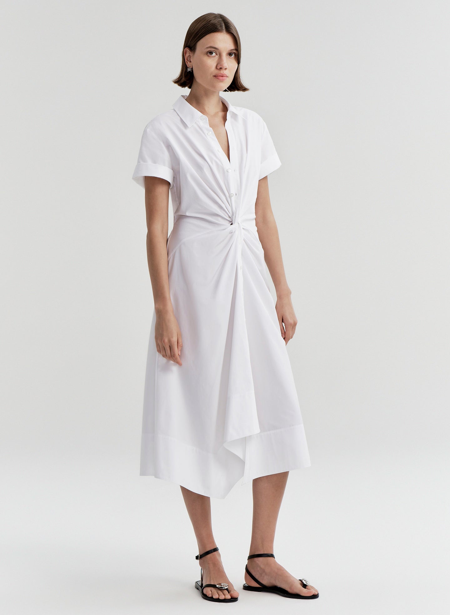 Woman wearing a white dress with a knot detail on a white background