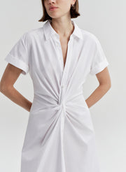 Woman wearing a white short-sleeve dress with a knot detail on a light gray background