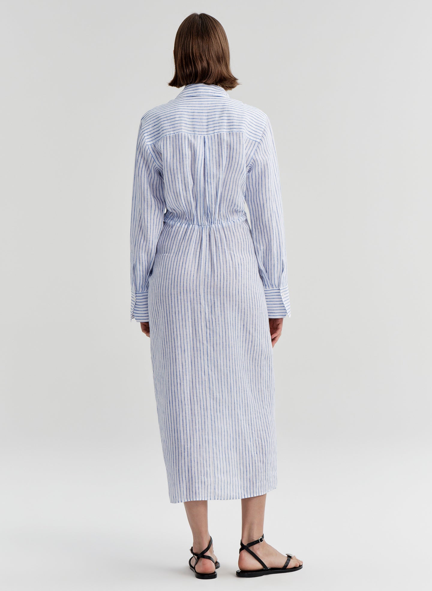 Woman wearing a blue and white striped dress on a plain background