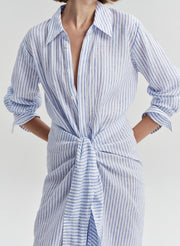Woman wearing a blue and white striped dress with a knot detail on a plain background
