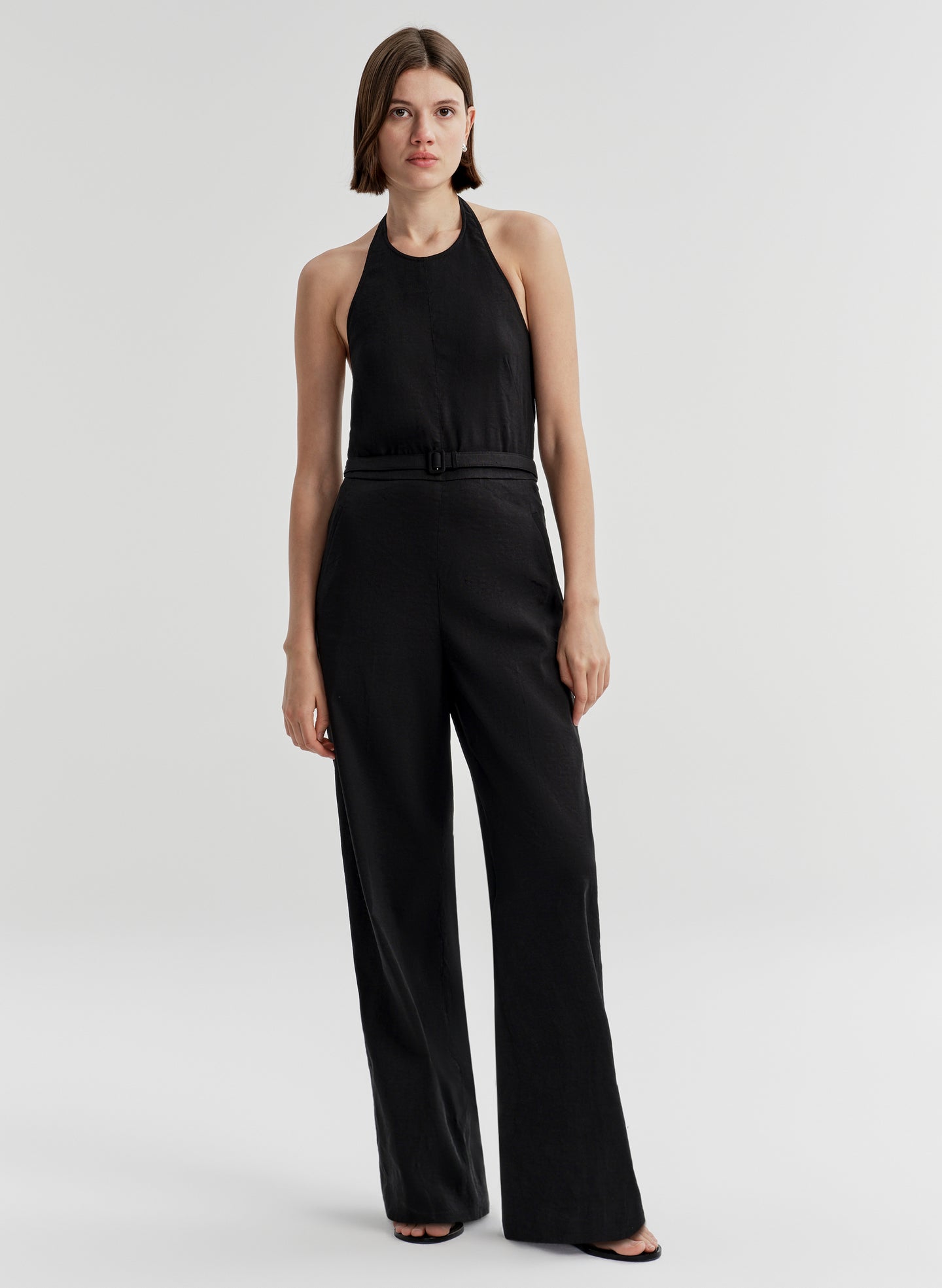 Woman wearing a black jumpsuit on a light gray background