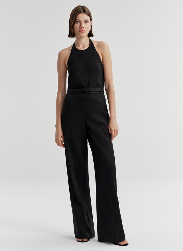 Woman wearing a black jumpsuit on a light gray background