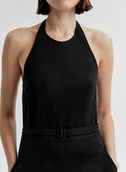 Woman wearing a black halter  jumpsuit on a light gray background