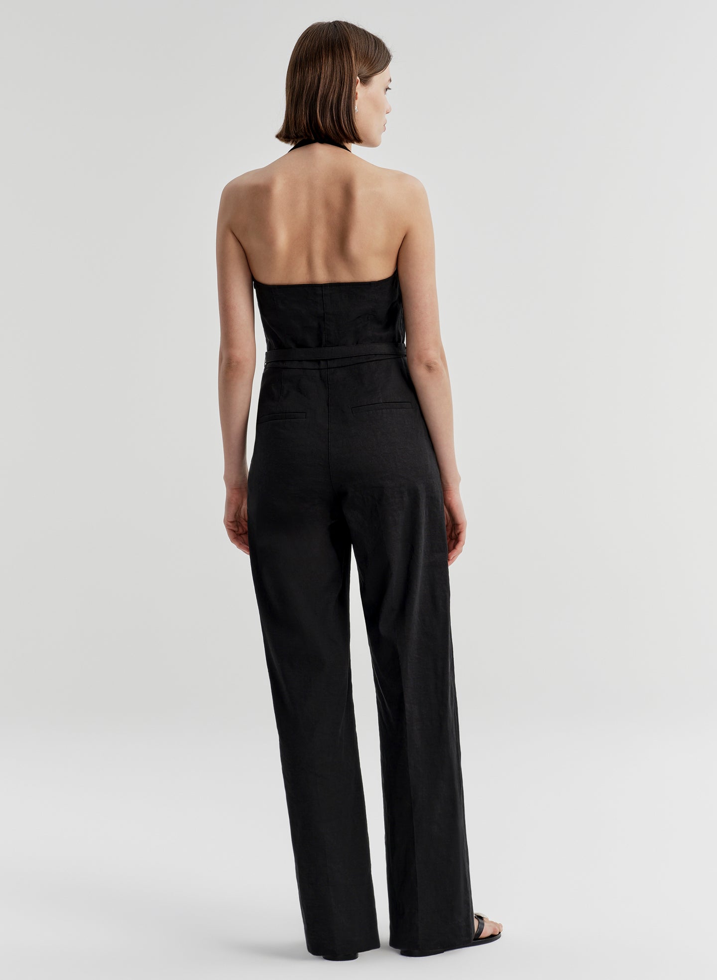 Woman wearing a black strapless jumpsuit on a white background