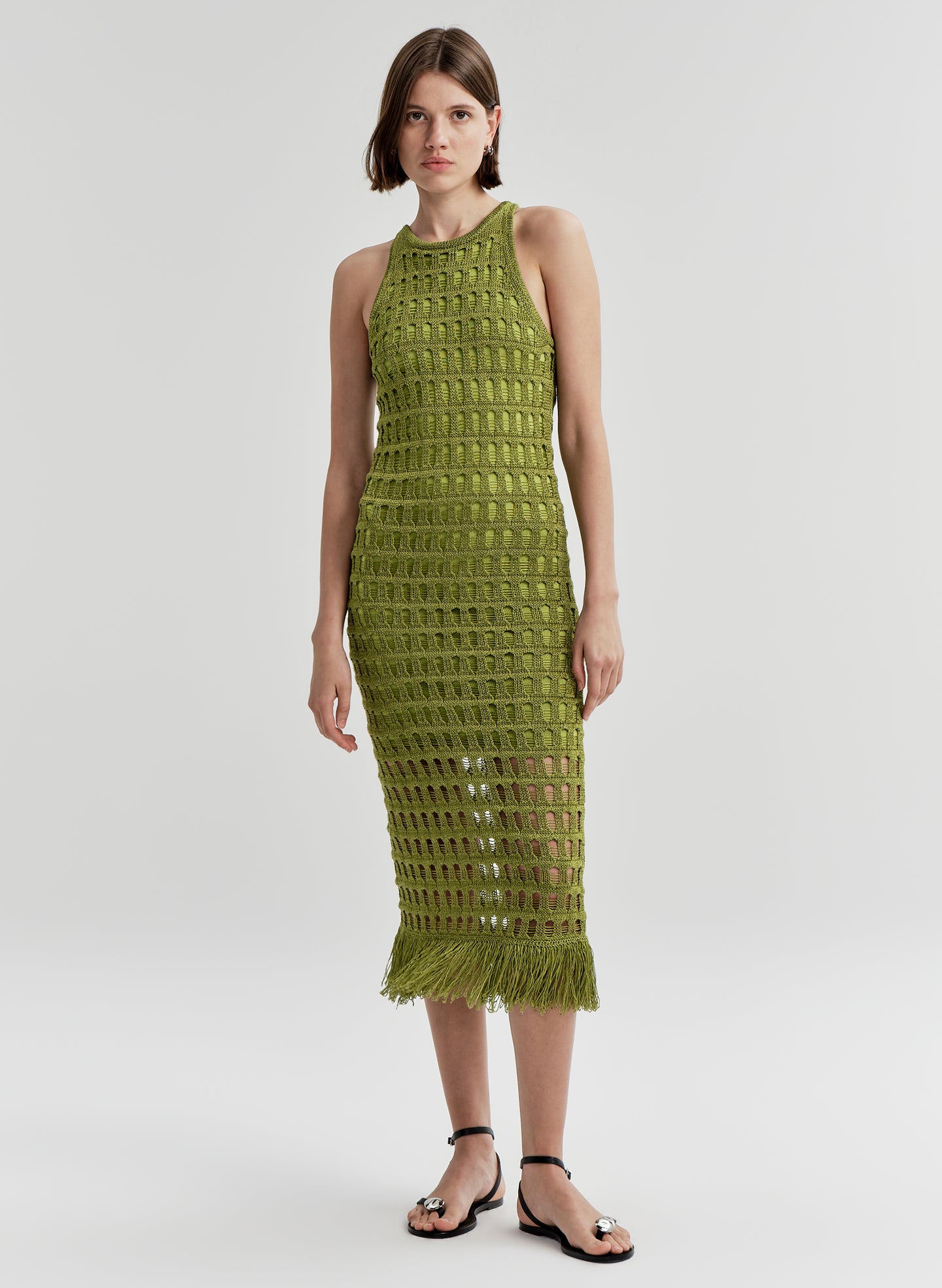 Woman wearing a green crochet dress on a light gray background