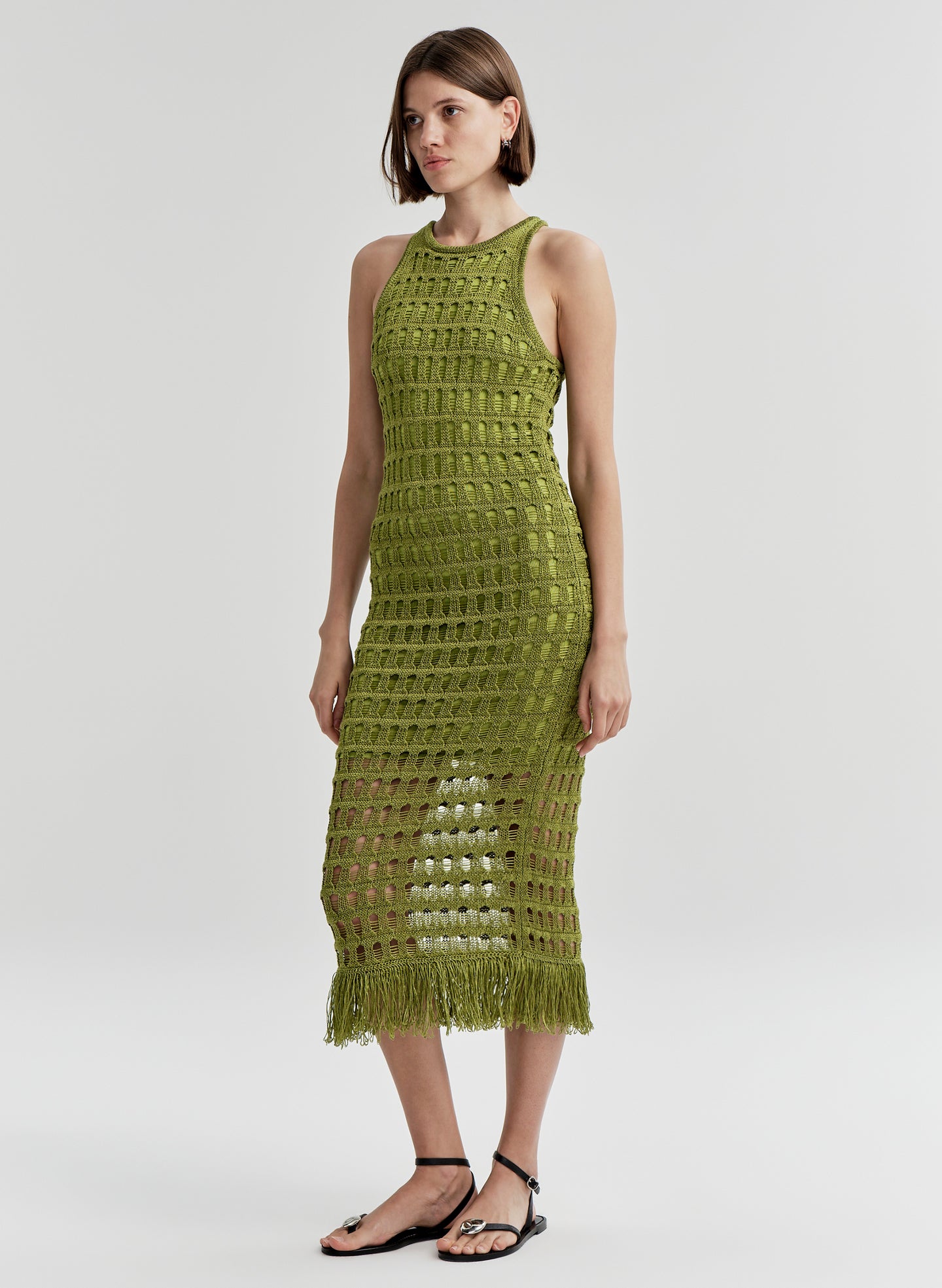 Woman wearing a green crochet dress on a white background