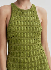 Woman wearing a green crochet sleeveless dress on a plain background