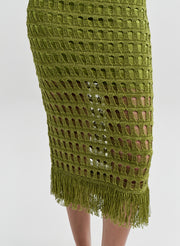 Woman wearing a green crochet dress with fringe detail on a white background
