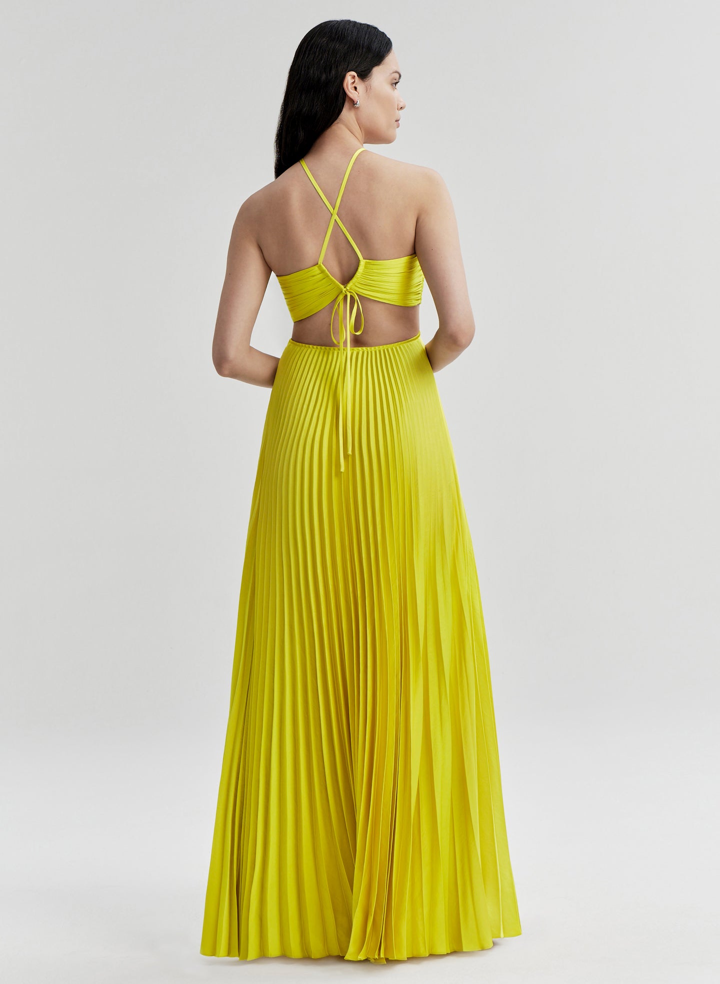 Woman wearing a yellow dress with thin straps on a light gray background