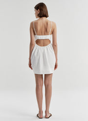 Woman wearing a white dress with cut-out design on a plain background