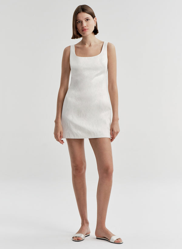 Woman wearing a white sleeveless dress on a plain background