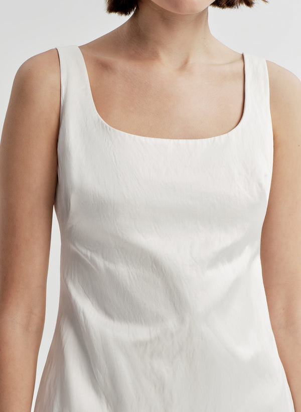 Woman wearing a white sleeveless dress on a plain background