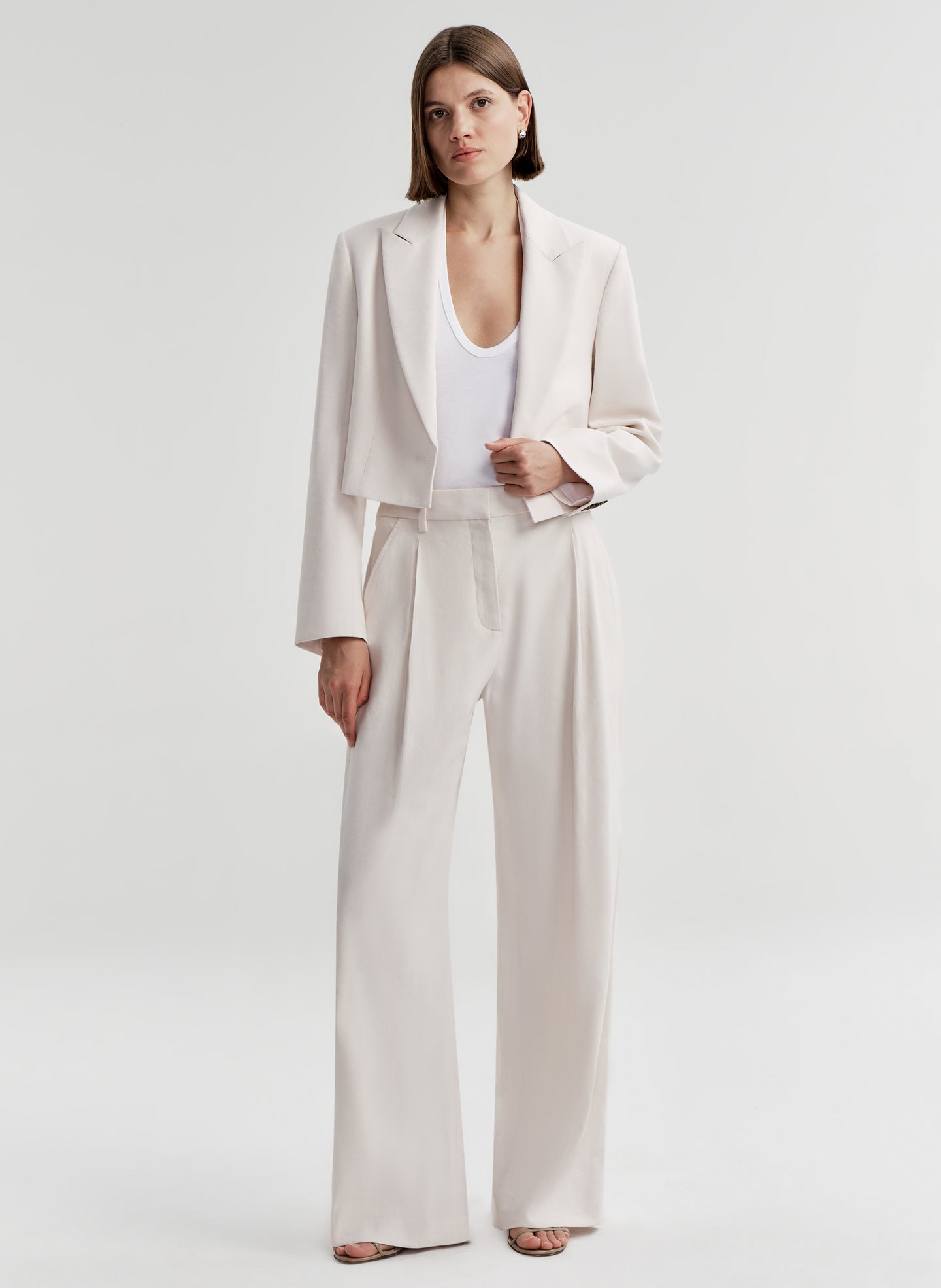 Woman wearing cream colored linen pants with a matching jacket 
